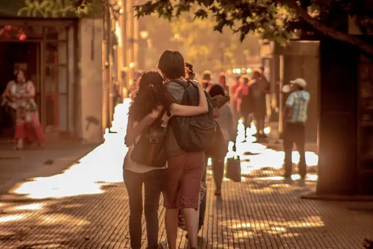 An engaged couple embracing walking down a street 