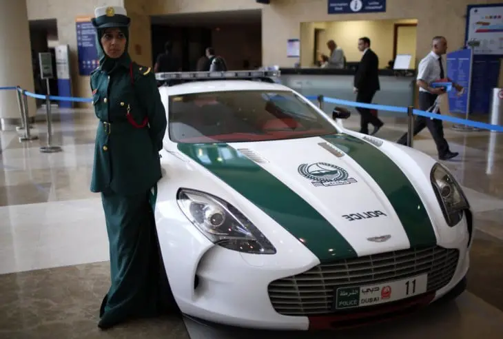 Female Dubai Police officer on the side of one of the luxury patrol cars 