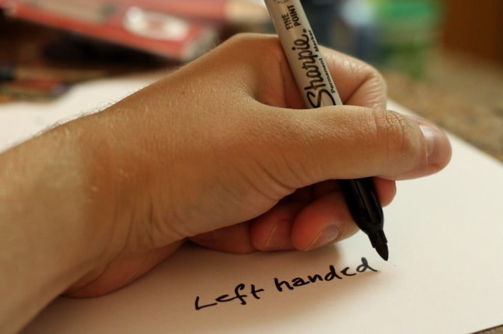 Left hand of a person writing with a pen on a paper 