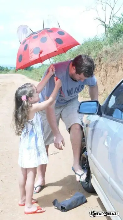 Little girl puts umbrella on her dad 