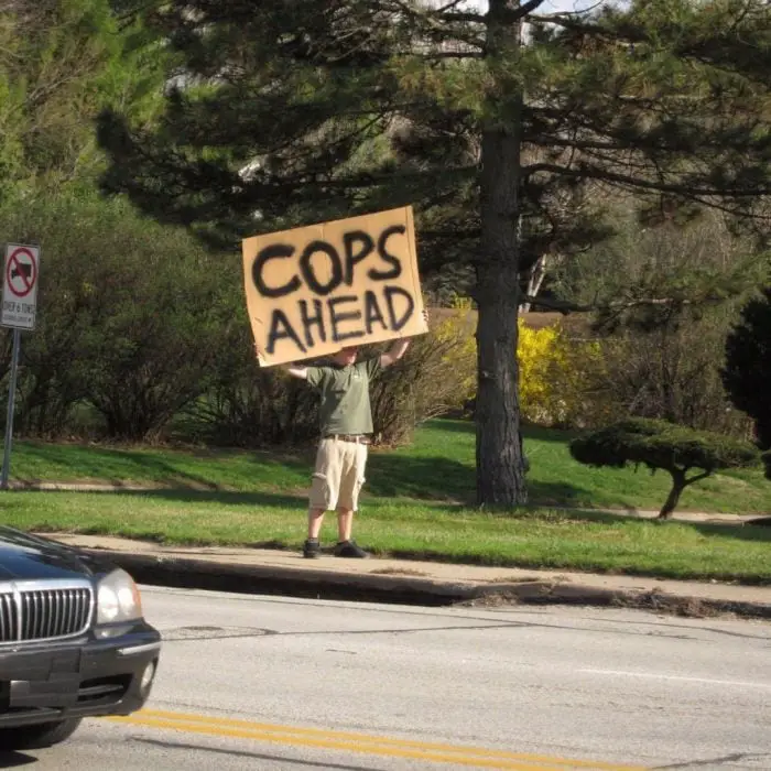 Man with a sign warning about police officers 
