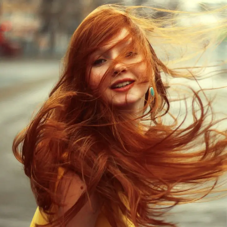 Photograph of a red-haired girl playing with her hair 