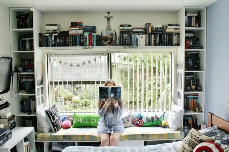 bookshelves framing a window and girl holding a book
