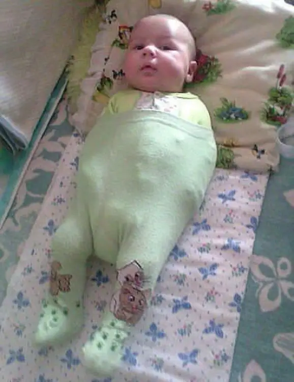 Baby lying with a pant holding her arms 