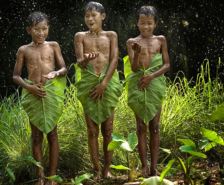 Children cover themselves with palm fronds