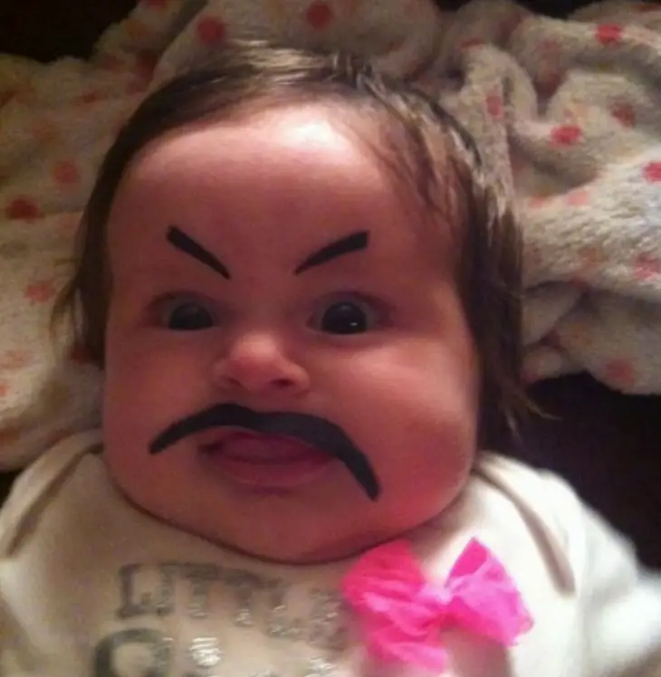 Face of a baby girl with moustaches and false eyebrows 