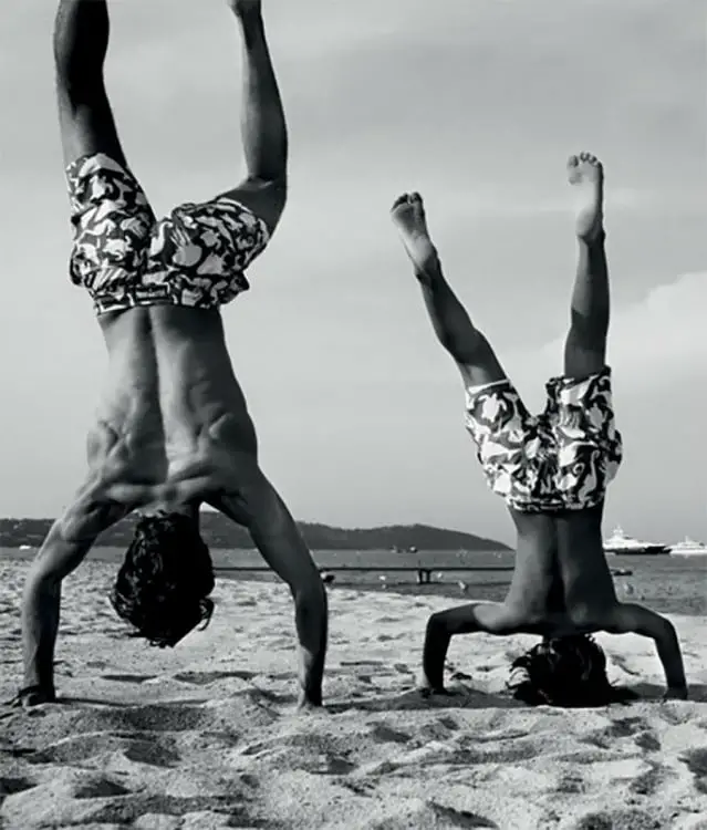 Father and son handstand on a beach 