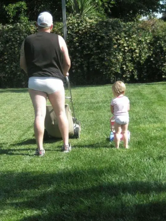 Father and son mowing the grass in underpants