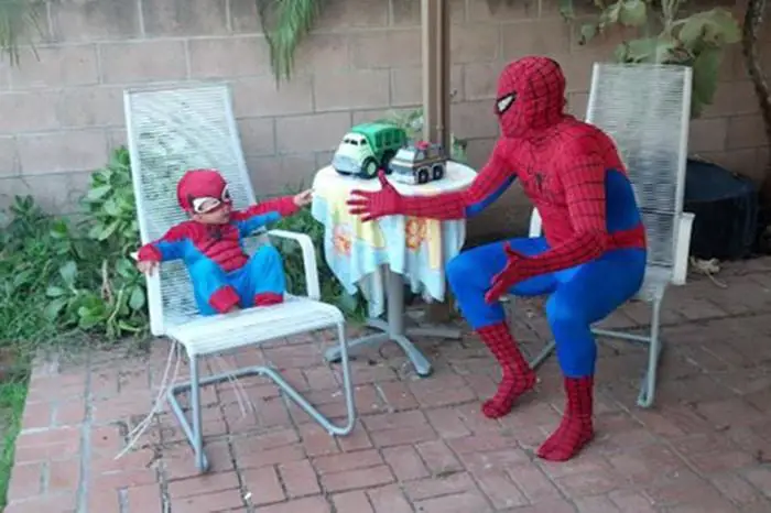 Father and sons dressed as Spiderman sitting in a home garden