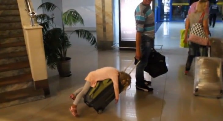 LITTLE GIRL ASLEEP ON HER DAD'S SUITCASE AT THE AIRPORT