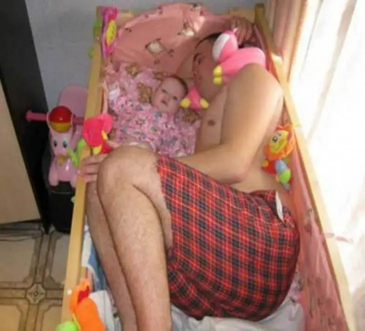 Man asleep in his baby's crib 