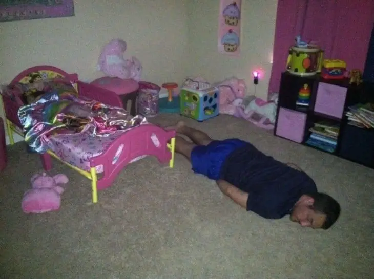 Man asleep on the floor of his daughter's room while she sleeps 