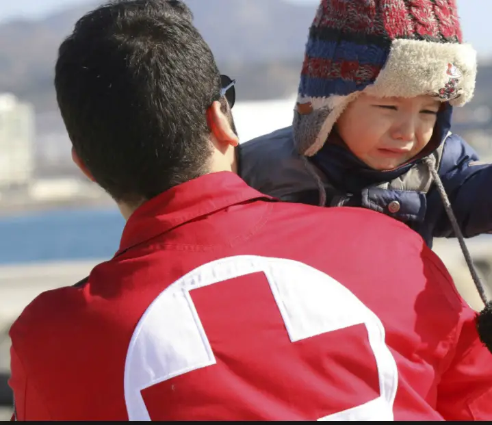 Man in red jacket carrying child