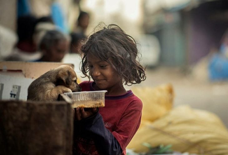 Poor little girl feeding a dog 