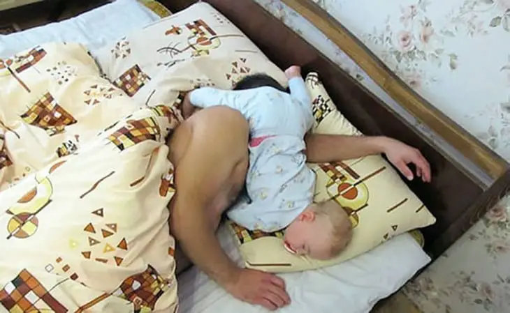Sleeping man with his baby on his face 